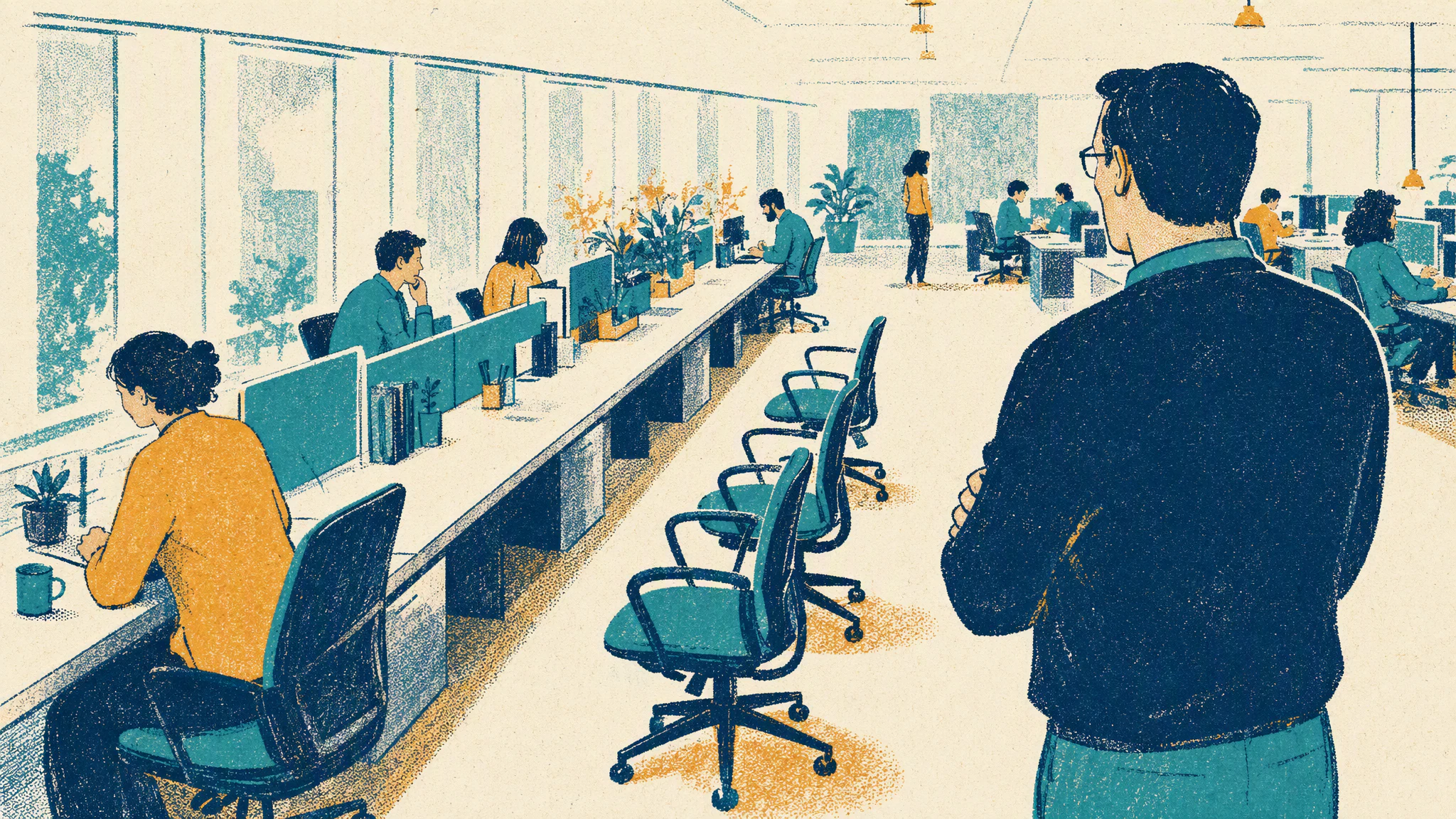 An empty office chair pushed back from a long shared desk where three colleagues carry on working.